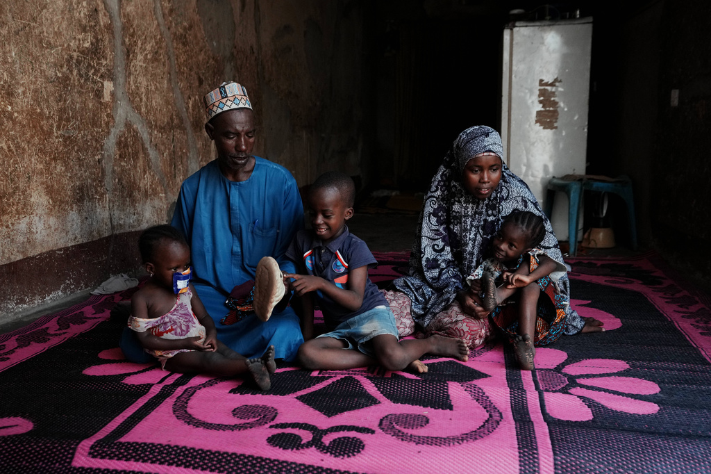 Shehu Aminu, second left, who lost his job as a taxi driver due to a spike in the retail price of petrol in February, sits with his wife Maryam Aminu, their daughter Farisa, left, who has relapsed into malnutrition, and her siblings, at their house in Kware Sokoto, northwestern Nigeria, Wednesday, July 15, 2026. (AP Photo/Sunday Alamba)