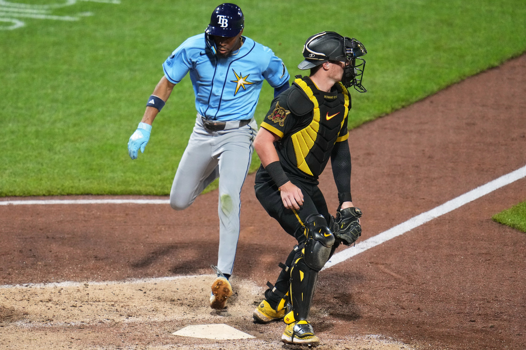 Tampa Bay Rays' Chandler Simpson, left, score behind Pittsburgh Pirates catcher Henry Davis, on a single by Junior Caminero off pitcher Bubba Chandler during the sixth inning of a baseball game in Pittsburgh, Friday, April 17, 2026. (AP Photo/Gene J. Puskar)