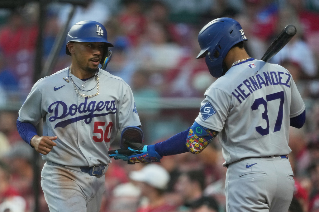 Los Angeles Dodgers' Mookie Betts (50) celebrates with Teoscar Hernández (37) after scoring on a double hit by Will Smith during the third inning of a baseball game against the Cincinnati Reds, Wednesday, Sept. 16, 2026, in Cincinnati. (AP Photo/Carolyn Kaster)