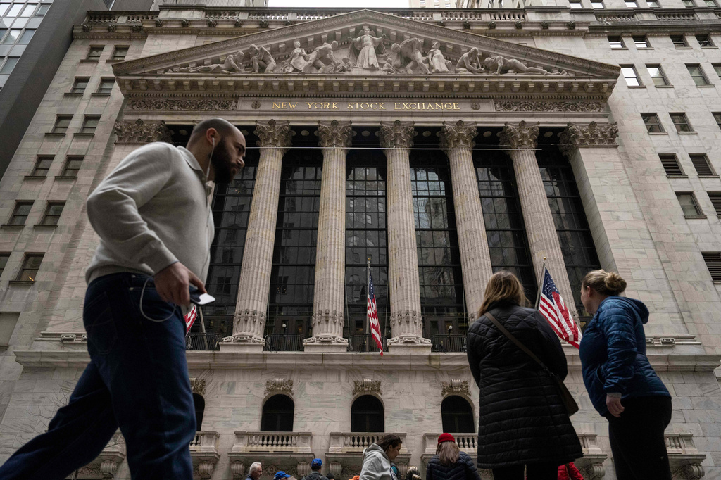 People walk past the New York Stock Exchange, Friday, March 27, 2026, in New York. (AP Photo/Yuki Iwamura)
