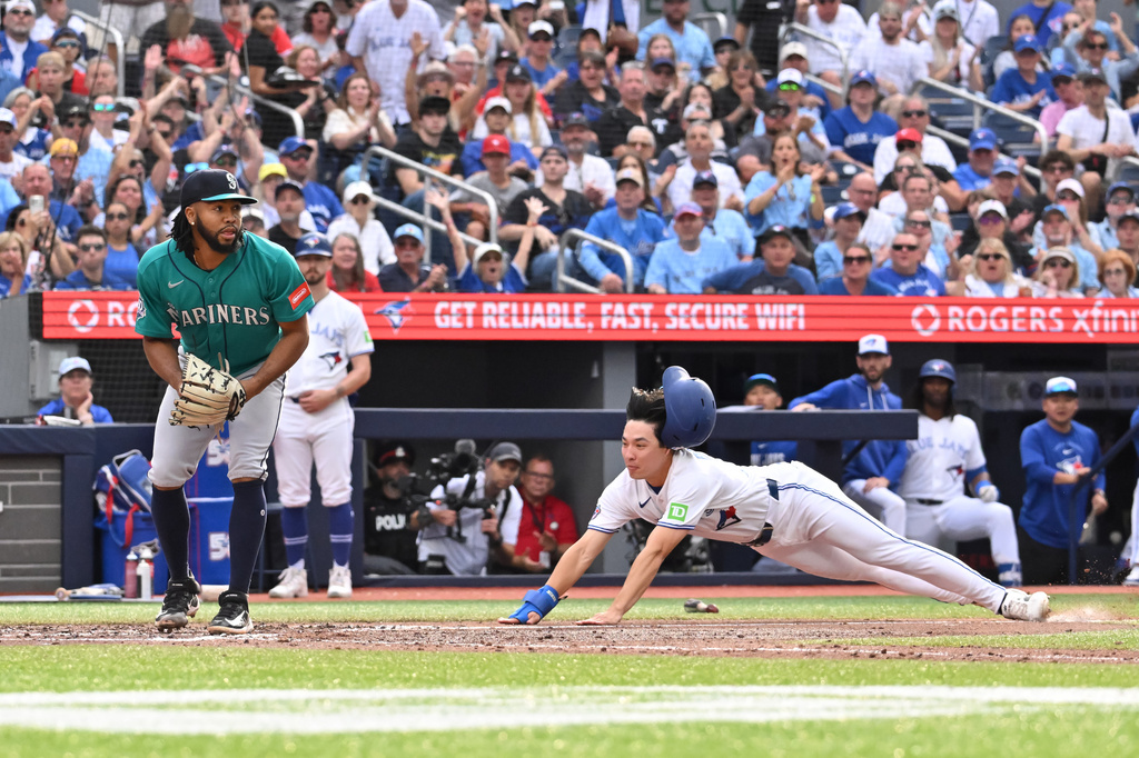 Toronto Blue Jays' Brett Bateman, right, scores on a wild pitch as Seattle Mariners left fielder Randy Arozarena (56) looks on during the fifth inning of a baseball game in Toronto, Saturday, Aug. 29, 2026. (Jon Blacker/The Canadian Press via AP)