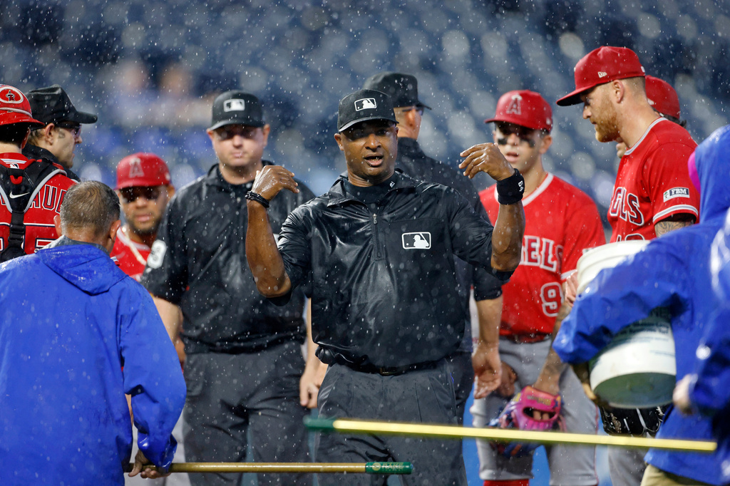 Umpire Alan Porter, center, calls for a rain delay as Los Angeles Angels players and members of the Kansas City Royals grounds crew stand on the pitchers mound during the seventh inning of a baseball game in Kansas City, Mo., Sunday, April 26, 2026. (AP Photo/Colin E. Braley)