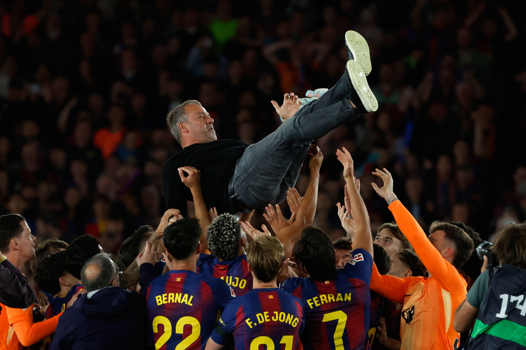 Barcelona head coach Hansi Flick is lifted by his players after winning the Spanish La Liga soccer match against Real Madrid to clinch the Spanish league title in Barcelona, Spain, Sunday, May 10, 2026. (AP Photo/Joan Monfort)