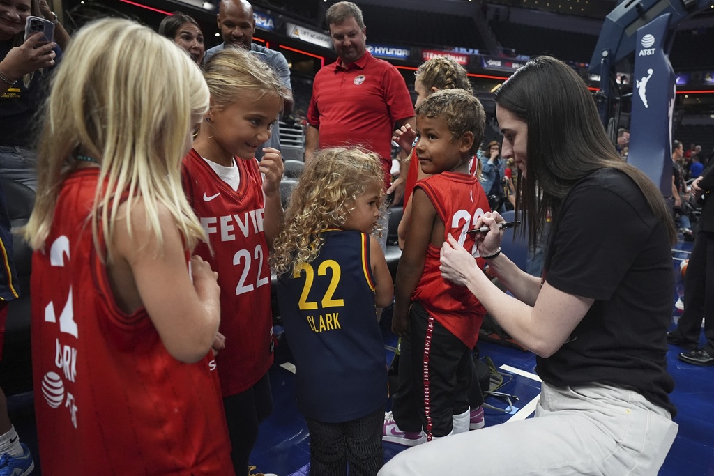 Indiana Fever's Caitlin Clark, right, gives autographs to young fans before a WNBA basketball game against the Minnesota Lynx, Friday, Aug. 22, 2025, in Indianapolis. (AP Photo/Darron Cummings)