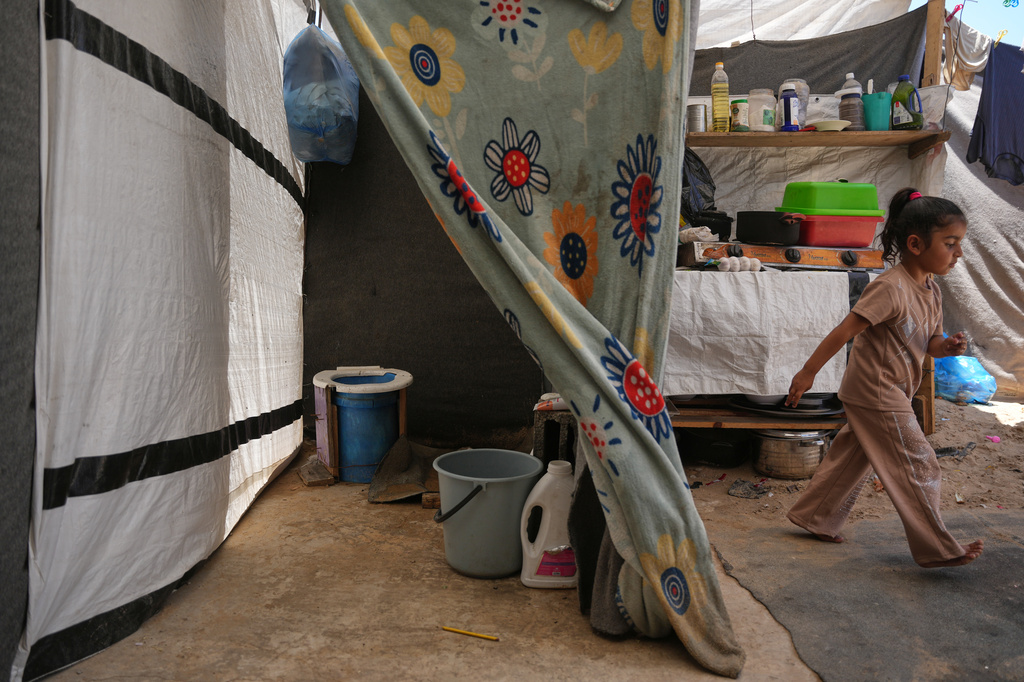 Wateen Darwish walks past her family's makeshift toilet at a camp for displaced Palestinians in Khan Younis, southern Gaza Strip, Wednesday, June 3, 2026. (AP Photo/Abdel Kareem Hana)