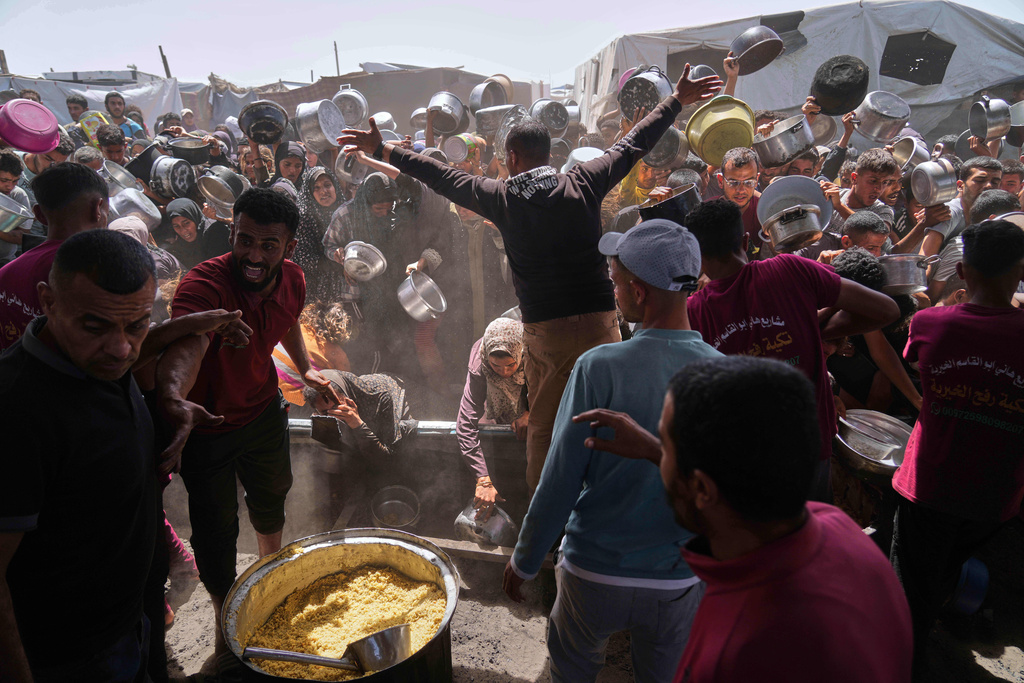 People struggle to get donated food at a community kitchen in Khan Younis, Gaza Strip, Friday, May 16, 2025. (AP Photo/Abdel Kareem Hana)