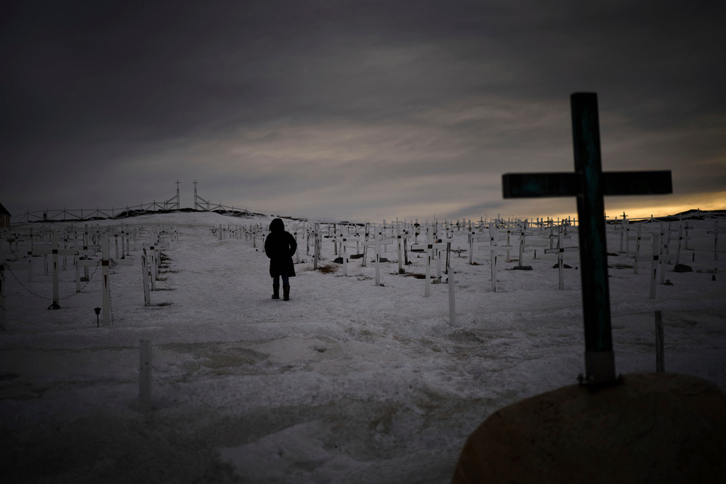 FILE - A woman walks at a graveyard covered by snow as the sun sets in Nuuk, Greenland, on Feb. 16, 2025. (AP Photo/Emilio Morenatti, File)