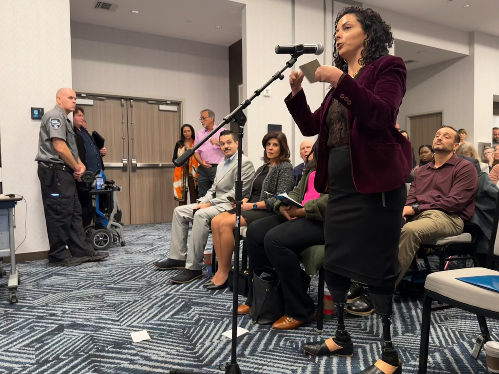 Jamie Schanbaum, whose legs and fingers were amputated after she contracted meningitis as a college student, testifies in support of vaccine mandates at a public hearing held by the Florida Department of Health on Friday, Dec. 12, 2025 in Panama City Beach, Fla. (AP Photo/Kate Payne)
