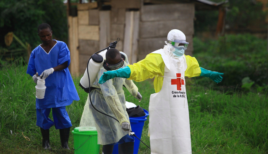 FILE - A health worker sprays disinfectant on his colleague after working at an Ebola treatment center in Beni, eastern Congo, Sept 9, 2018. (AP Photo/Al-hadji Kudra Maliro, File)