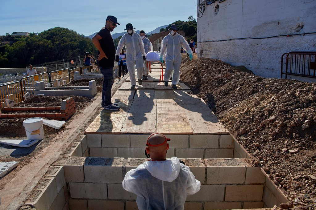 Funeral workers prepare to bury the body of a migrant who died while trying to cross from Morocco into the Spanish exclave of Ceuta, Friday, Aug. 21, 2026. (AP Photo/Antonio Sempere)
