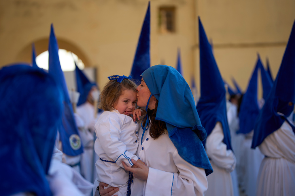 A hooded penitent of the Nuestro Padre Jesus Cautivo y Nuestra Senora de la Estrella brotherhood kisses her child during a Holy Week procession in Dona Mencia, southern Spain, Tuesday, March 31, 2026. (AP Photo/Manu Fernandez)