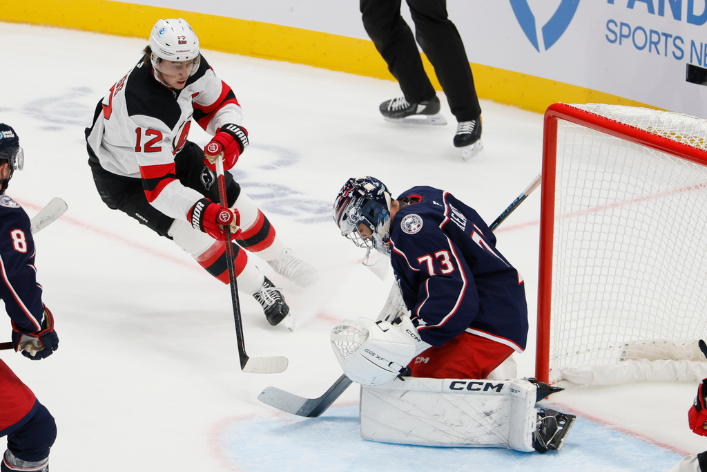 Columbus Blue Jackets' Jet Greaves, right, makes a save against New Jersey Devils' Cody Glass (12) during the second period of an NHL hockey game, Monday, Oct. 13, 2025, in Columbus, Ohio. (AP Photo/Jay LaPrete)