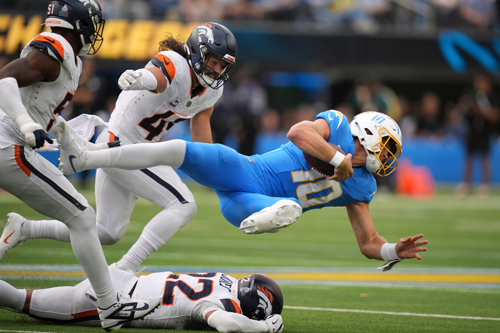 Los Angeles Chargers quarterback Justin Herbert, right, is taken down by Denver Broncos linebacker Que Robinson, left, linebacker Alex Singleton, second from left, and safety Brandon Jones during the second half of an NFL football game, Sunday, Oct. 11, 2026, in Inglewood, Calif. (AP Photo/Gregory Bull)