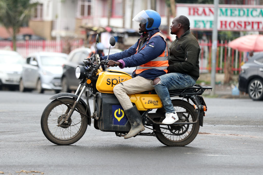 A man rides an electric Spiro motorcycle carrying a passenger in Nairobi, Kenya, Tuesday, Feb. 24, 2026. (AP Photo/Henry Naminde)