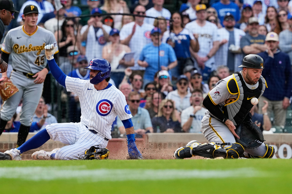 Chicago Cubs' Dansby Swanson, left, scores past Pittsburgh Pirates catcher Joey Bart during the seventh inning of a baseball game, in Chicago, Sunday, April 12, 2026. (AP Photo/Nam Y. Huh)