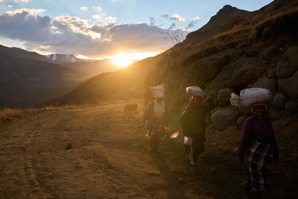 FILE - Women carry bags of food in the mountains of Ha Lejone, Lesotho, July 14, 2025. (AP Photo/Bram Janssen, File)