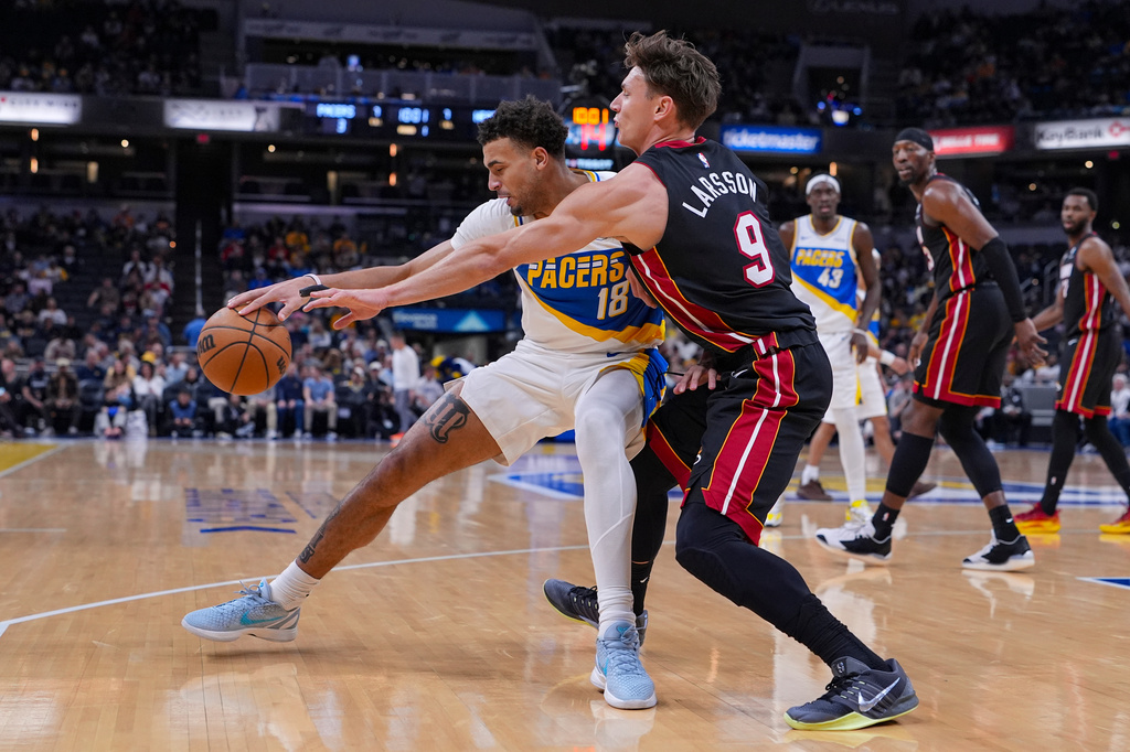 Miami Heat guard Pelle Larsson (9) defends Indiana Pacers forward Jalen Slawson (18) during the first half of an NBA basketball game in Indianapolis, Sunday, March 29, 2026. (AP Photo/Michael Conroy)