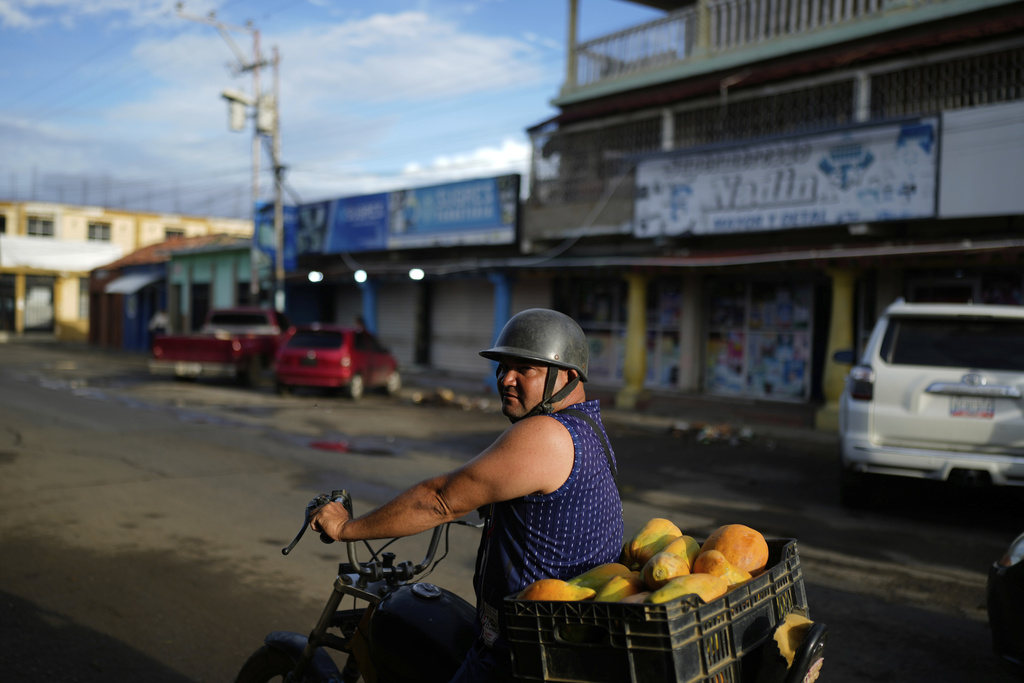 A vendor sells papayas from a motorcycle in Coro, Venezuela, Sunday, June 29, 2025. (AP Photo/Ariana Cubillos)