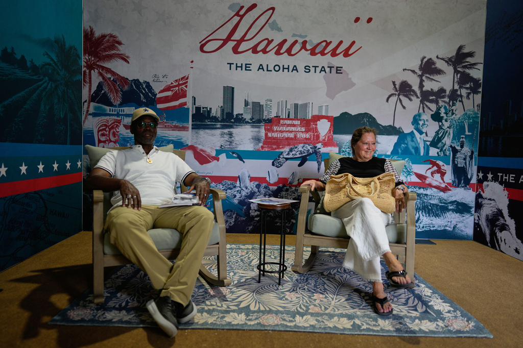 Alonzo Lewis Jr, and Kelly Domizio sit in cushy chairs in Hawaii's exhibit during the Great American State Fair on Friday, June 26, 2026, in Washington. (AP Photo/Carolyn Kaster)