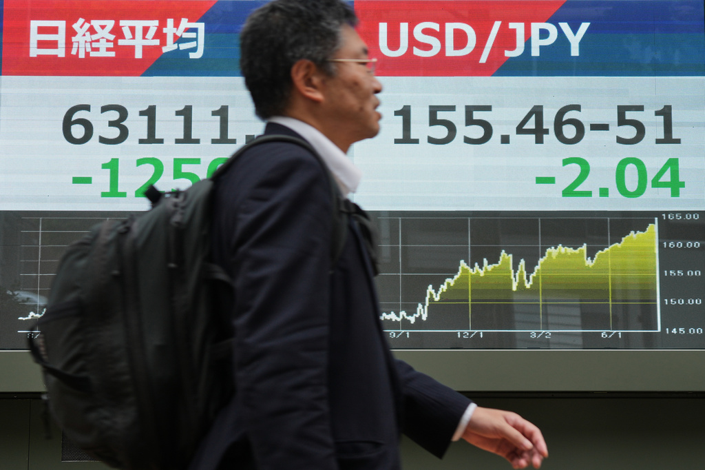A person walks past an electronic board showing Japan's Nikkei index and U.S. dollar and Japanese yen exchange rate at a securities firm in Tokyo Monday, Aug. 3, 2026. (AP Photo/Eugene Hoshiko)