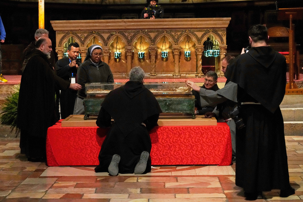 Friars and a nun pray before the remains of Francis of Assisi inside the Basilica of St. Francis of Assisi in Assisi, Italy, Saturday, Feb. 21, 2026, on the eve of a public exposition beginning Feb. 22 to mark the 800th anniversary of his death in 1226. (AP Photo/Gregorio Borgia)
