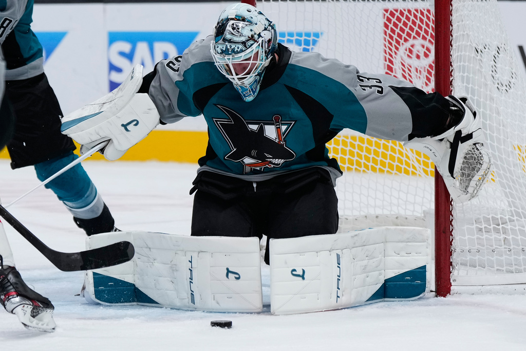 San Jose Sharks goaltender Alex Nedeljkovic (33) deflects the puck during the second period of an NHL hockey game against the New Jersey Devils, Thursday, Oct. 30, 2025, in San Jose, Calif. (AP Photo/Godofredo A. Vásquez)