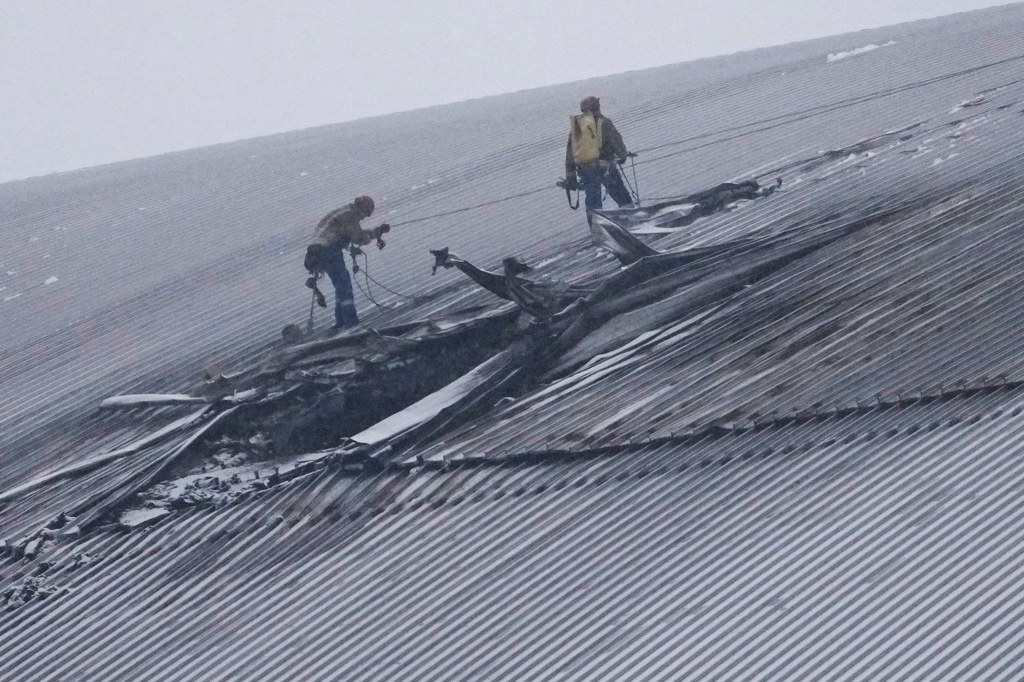 FILE - Workers examine the damage to the roof of the New Safe Confinement structure, which was built to contain the radioactive remains of Reactor No. 4 at the Chernobyl nuclear power plant, following what Ukrainian officials said was a Russian drone attack in Chernobyl, Ukraine, Feb. 14, 2025. (AP Photo/Efrem Lukatsky, File)