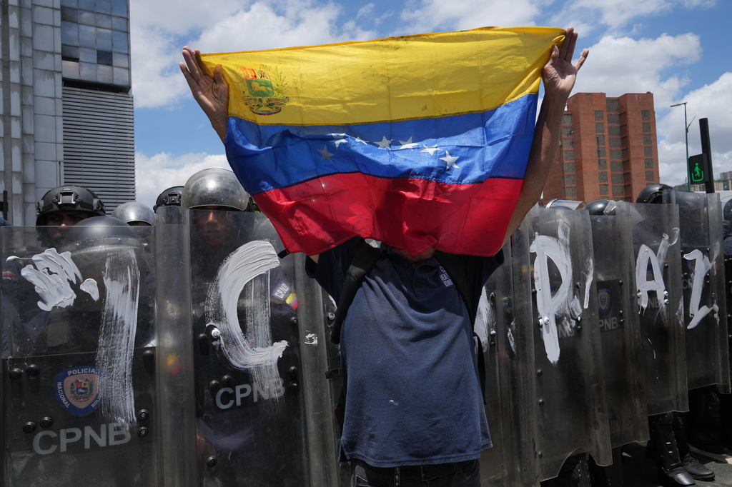 A man holds a Venezuela national flag during a protest calling for justice for Carmen Navas the day after her death in Caracas, Venezuela, Monday, May 18, 2026, a week after the government confirmed that her missing son Victor Hugo Quero had died in custody following his arrest about a year earlier. (AP Photo/Ariana Cubillos)