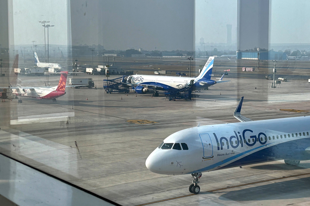 Two Indigo Airlines planes are seen through a glass window at the Indira Gandhi International Airport in New Delhi as several flights operated by the carrier were either cancelled or delayed, India, Thursday, Dec. 4, 2025. (AP Photo/Manish Swarup)