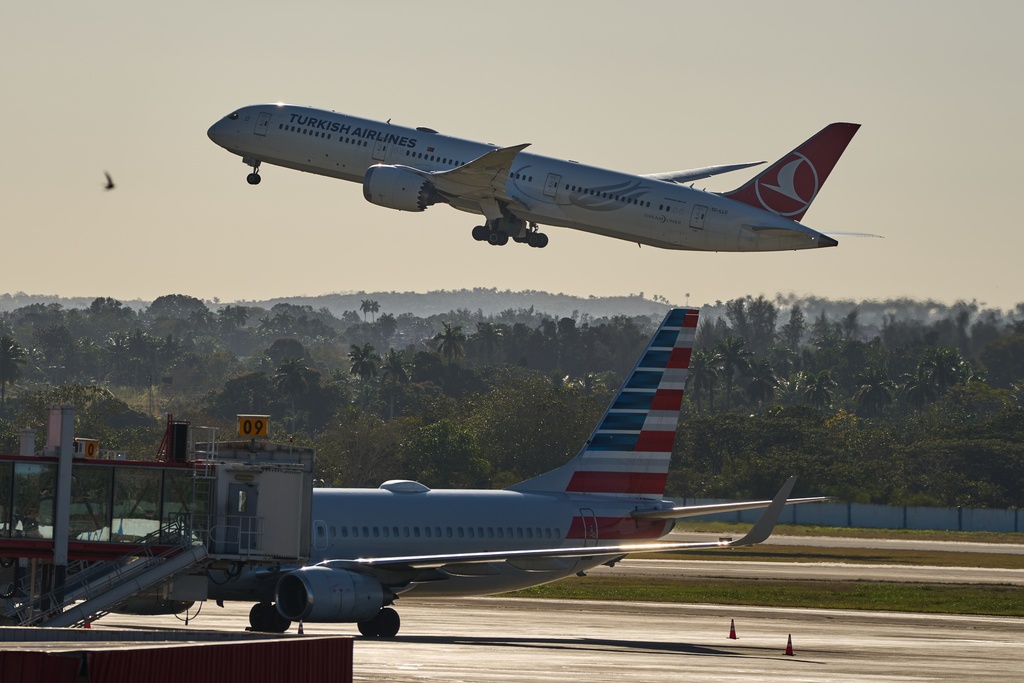 A Turkish Airlines plane takes off alongside an American Airlines plane at Jose Marti International Airport in Havana, Cuba, Monday, Feb. 9, 2026. (AP Photo/Ramon Espinosa)