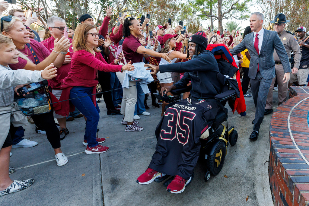 Florida State linebacker Ethan Pritchard (35) greets fans as he enters the stadium with head coach Mike Norvell, right, before an NCAA college football game against Virginia Tech, Saturday, Nov. 15, 2025, in Tallahassee, Fla. (AP Photo/Colin Hackley)