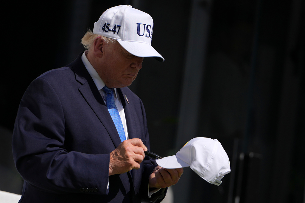 President Donald Trump signs a cap at the Presidents Cup golf tournament at Medinah Country Club, Sunday, Sept. 27, 2026, in Medinah, Ill. (AP Photo/Julia Demaree Nikhinson)
