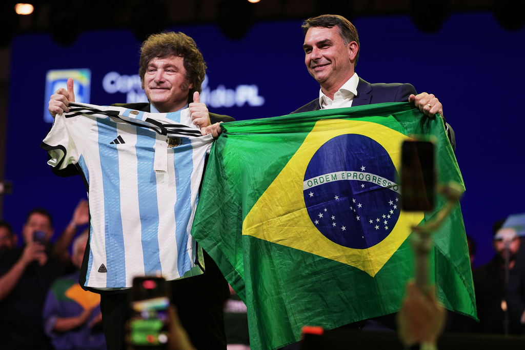 Brazilian Sen. Flavio Bolsonaro holds a Brazil national flag as Argentina's President Javier Milei holds an Argentina local selection jersey, during the Liberal Party convention where Bolsonaro was confirmed as the party's presidential candidate, in Sao Paulo, Saturday, July 25, 2026. (AP Photo/Ettore Chiereguini)