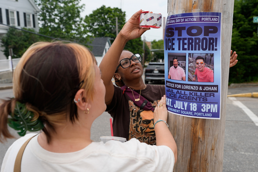 Angeliki Cintron, left, and Saidi Moseley post a notice of an upcoming gathering in response to the recent killings by U.S. Immigration and Customs Enforcement agents, in Biddeford, Maine, Wednesday, July 15 2026. (AP Photo/Robert F. Bukaty)