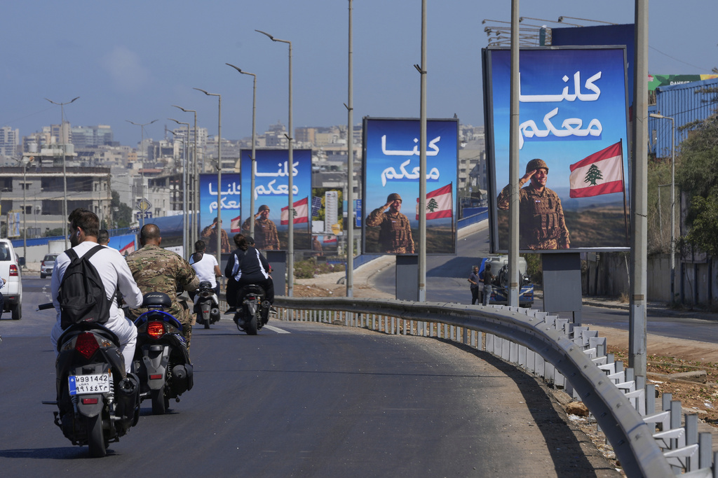 People on scooters drive past billboards in support of the Lebanese army with Arabic reading: "We are all with you," set up on the highway leading to Beirut international airport, in Beirut, Lebanon, Sept. 3, 2025. (AP Photo/Hussein Malla)