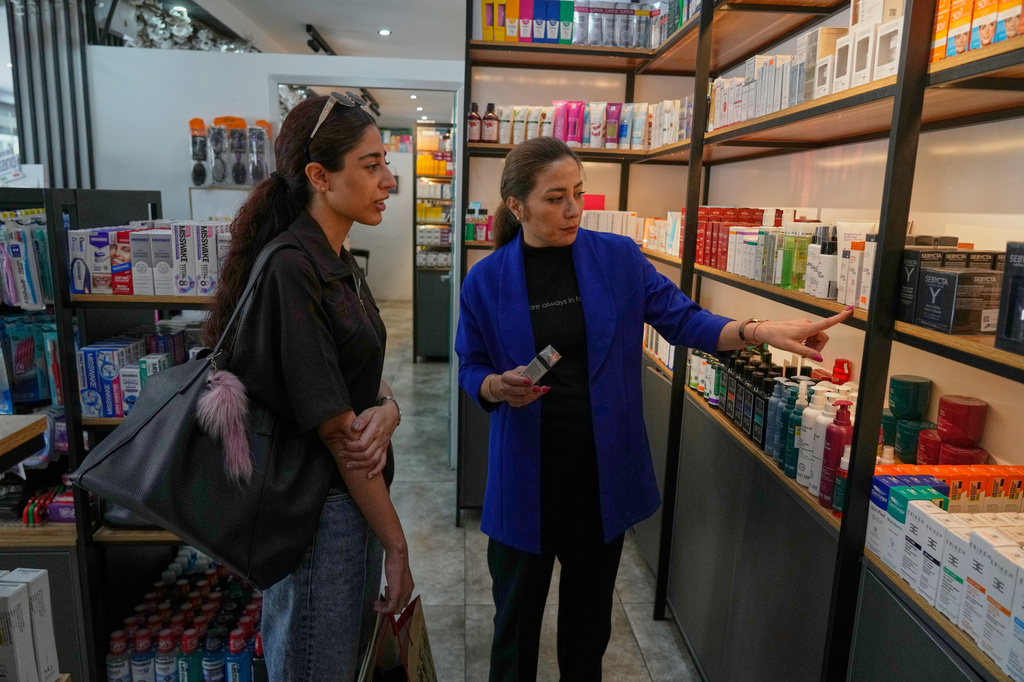 Pharmacy technician Mina Mohammadian talks about cosmetics to a customer at a pharmacy in Tehran, Iran, Friday, Aug. 21, 2026. (AP Photo/Vahid Salemi)