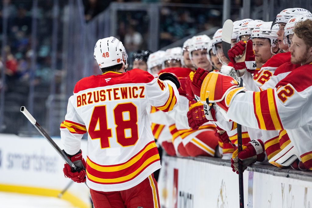 Calgary Flames defenseman Hunter Brzustewicz (48) high-fives the bench after scoring during the second period of an NHL hockey game against the Seattle Kraken, Saturday, April 11, 2026, in Seattle. (AP Photo/Maddy Grassy)