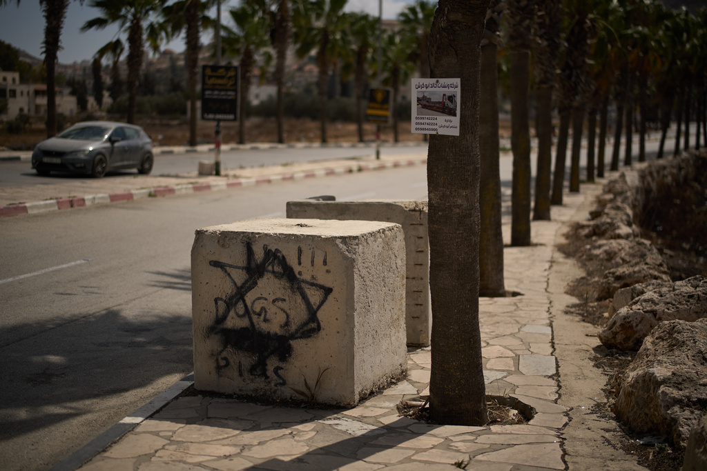 Concrete blocks set up by Israeli authorities are seen next to a gate at the entrance of the West Bank town of Turmus Ayya, Tuesday, Sept. 30, 2025. (AP Photo/Leo Correa)