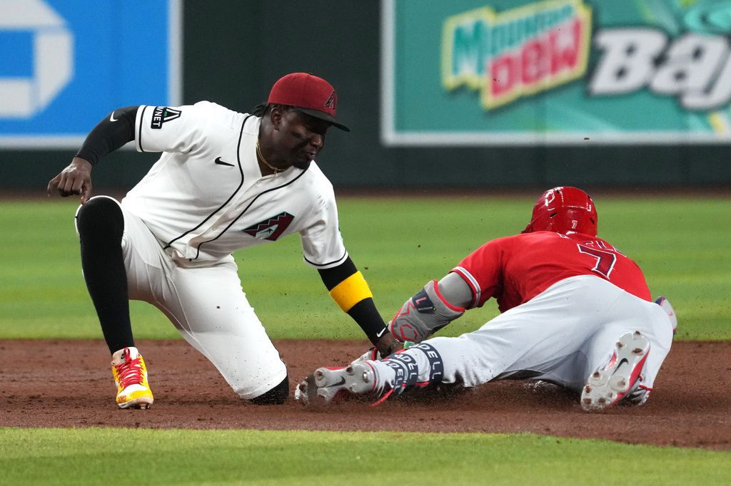 Los Angeles Angels' Jo Adell (7) advances to second base under a tag by Arizona Diamondbacks shortstop Geraldo Perdomo, left, in the third inning of a baseball game, Monday, June 15, 2026, in Phoenix. (AP Photo/Rick Scuteri)