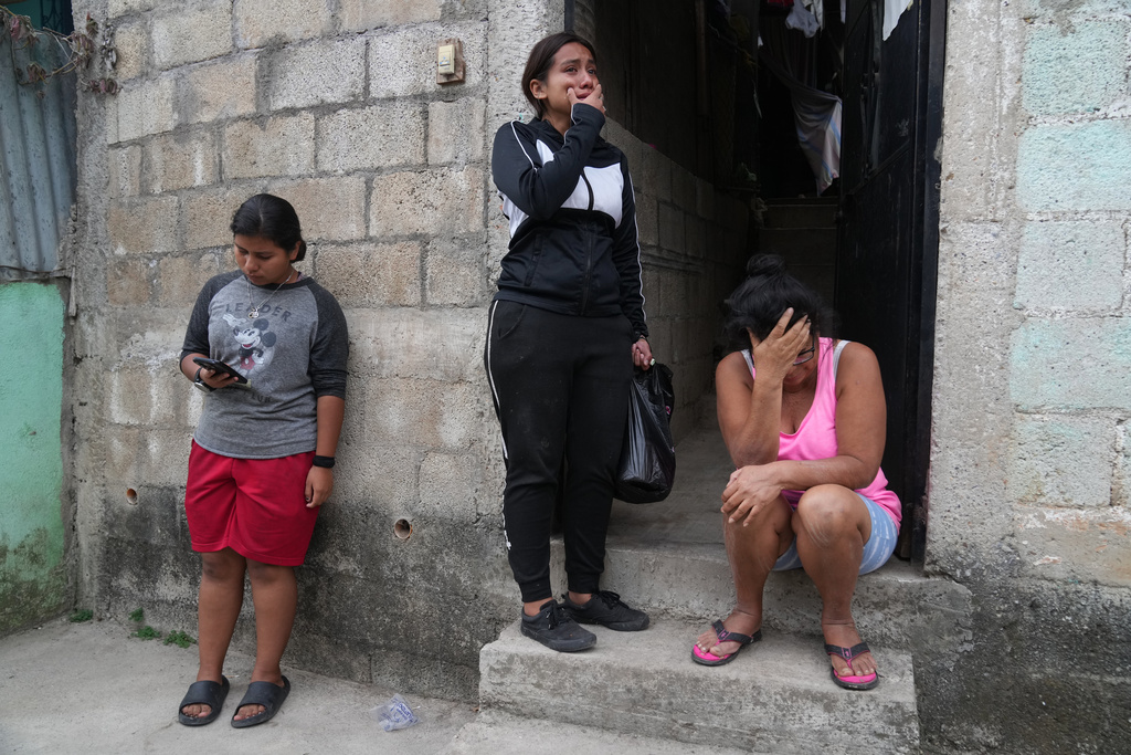 Locals react after finding the body of a neighbor inside their shared house during the country's state of emergency, following an escalation of gang-related violence, on the outskirts of Guatemala City, Tuesday, Jan. 20, 2026. (AP Photo/Moises Castillo)