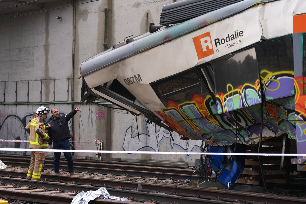 Police officers inspect the damage after a commuter train derailed as a retaining wall collapsed onto the tracks in Gelida, near Barcelona, Spain, Wednesday, Jan. 21, 2026. (AP Photo/Joan Mateu Parra)