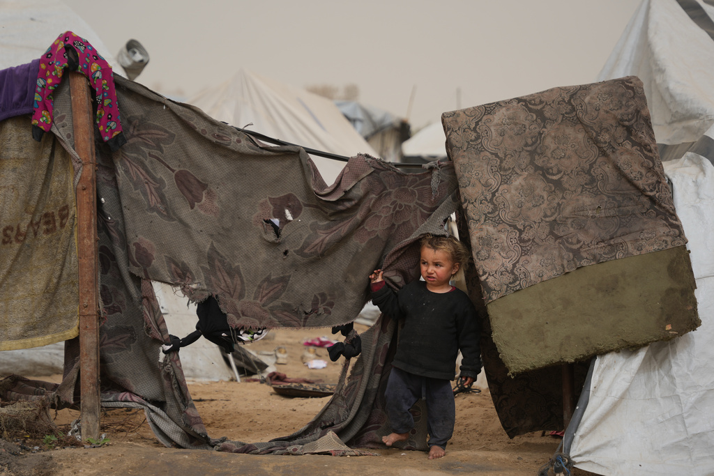 Palestinian child looks on as he stands next to a tent at a makeshift camp for displaced people during a dust storm in Zawaida, in the central Gaza Strip, Saturday, Feb. 14, 2026. (AP Photo/Abdel Kareem Hana)