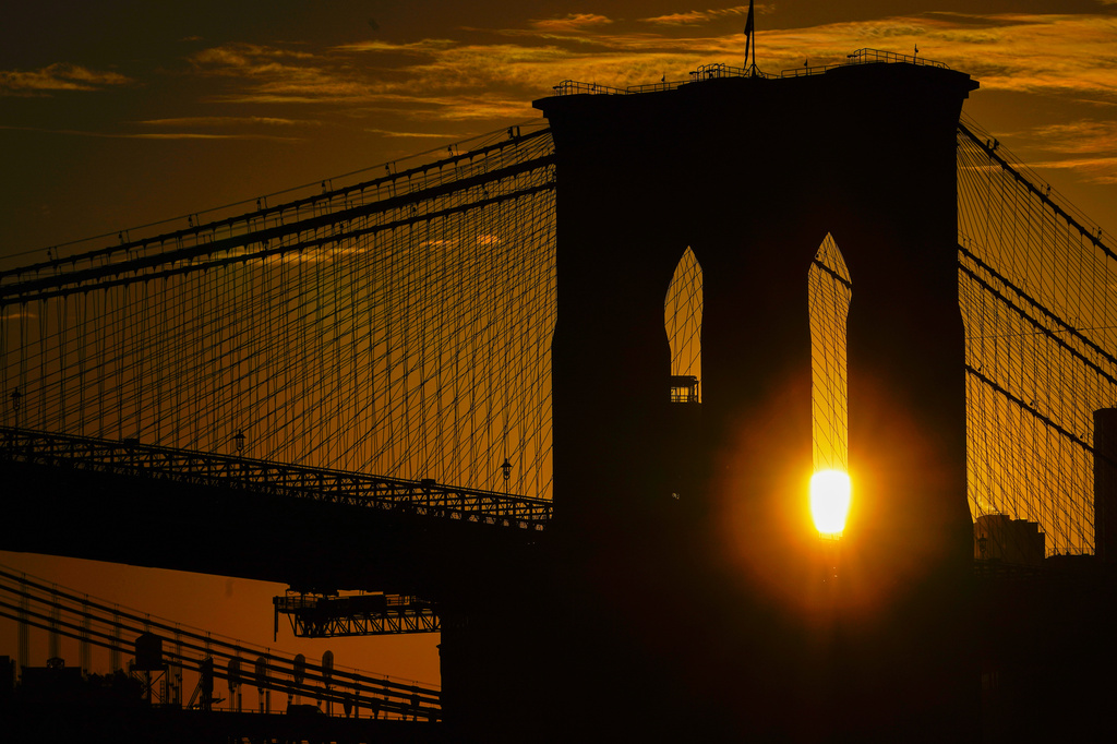 FILE - The sun rises behind the Brooklyn Bridge on Oct. 11, 2023, in New York. (AP Photo/Kiichiro Sato, File)