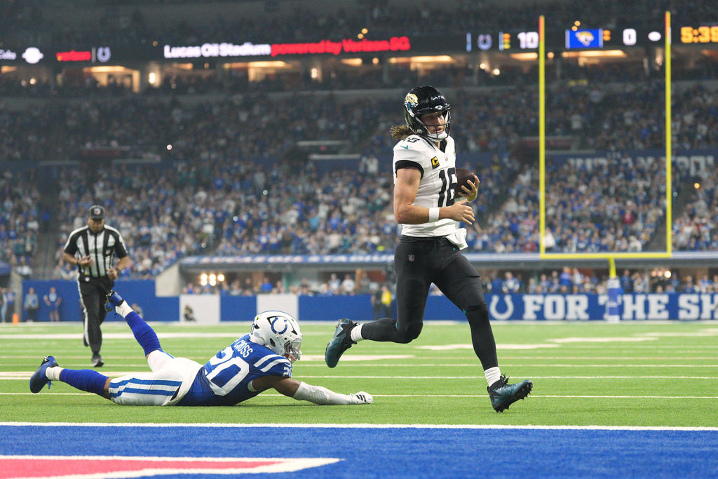 Jacksonville Jaguars quarterback Trevor Lawrence (16) scores past Indianapolis Colts safety Nick Cross (20) during the first half of an NFL football game Sunday, Dec. 28, 2025, in Indianapolis. (AP Photo/AJ Mast)