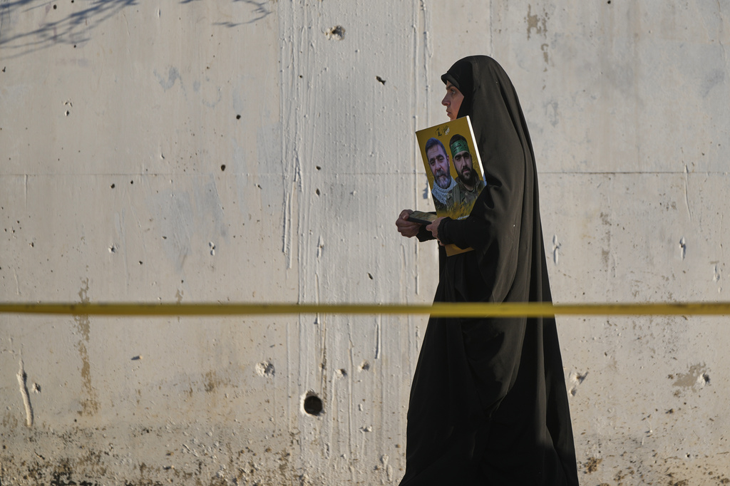 A woman holds a poster of Hezbollah fighters during a sermon marking the third day of Ashoura, the Shiite Muslim commemoration of the 7th-century death of Imam Hussein, the grandson of the Prophet Muhammad, in the southern port city of Tyre, Lebanon, Friday, June 19, 2026. (AP Photo/Hassan Ammar)