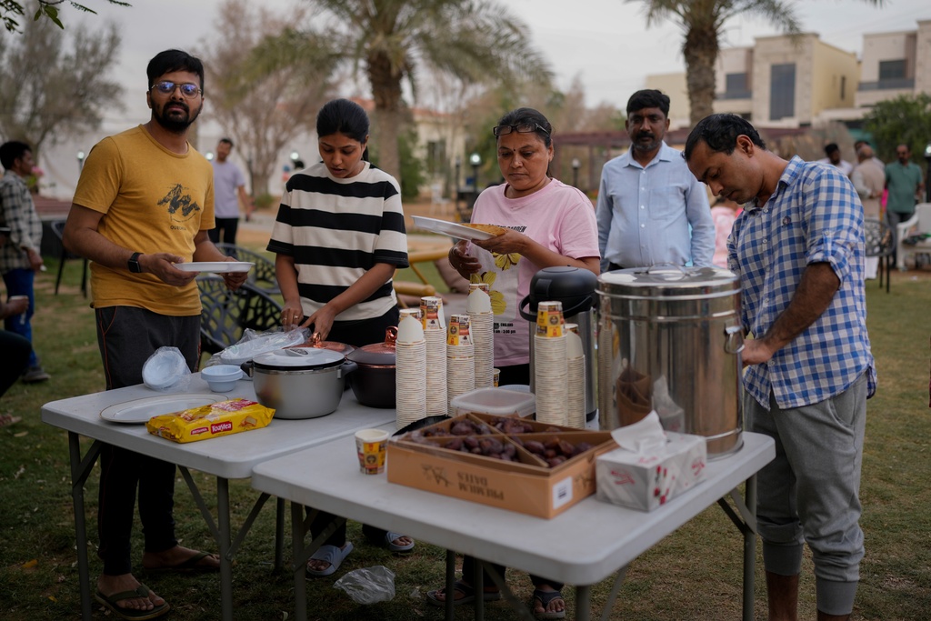 Stranded Indian travelers share evening tea and snacks at a farmhouse owned by an Indian businessman, now converted into a shelter in Ajman, near Dubai, United Arab Emirates, Saturday, March 7, 2026. (AP Photo/Altaf Qadri)