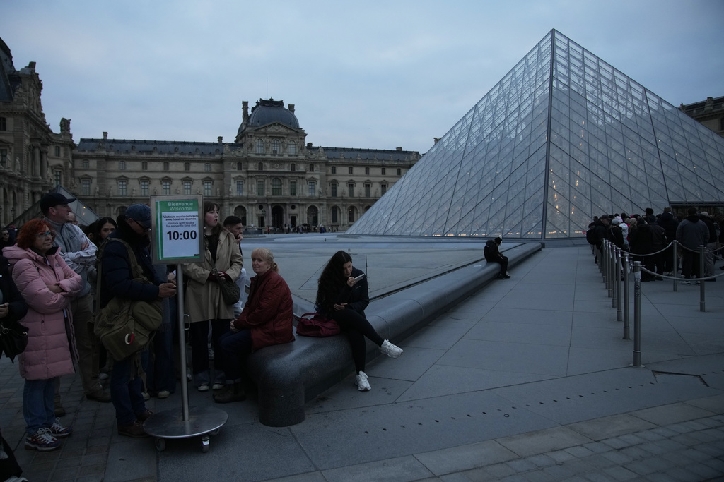 People wait at the entrance of the Louvre museum as employees were set to vote on whether to extend a strike that shut the world's most visited museum, as unions protest chronic understaffing, building deterioration and recent management decisions Wednesday, Dec. 17, 2025 in Paris. (AP Photo/Christophe Ena)