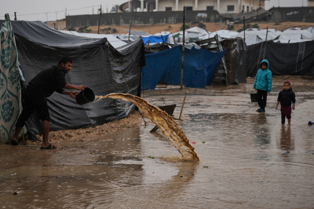 A man clears water from his tent at a camp for displaced Palestinians following heavy rain in Deir al-Balah, Gaza Strip, Thursday, Dec. 11, 2025. (AP Photo/Abdel Kareem Hana)