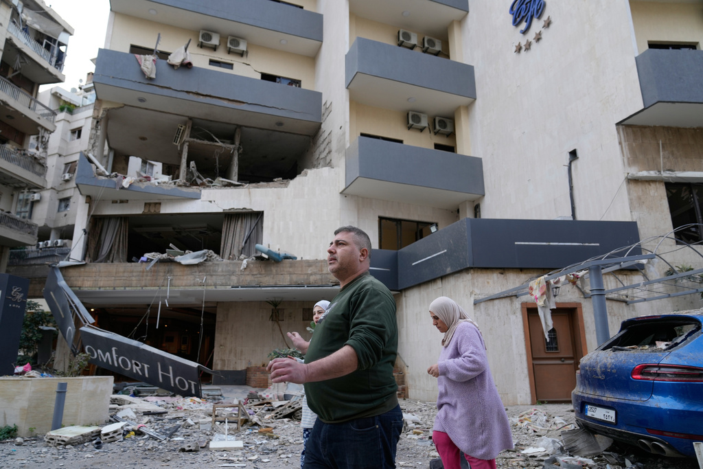 People pass in front of a damaged hotel that was hit by an Israeli airstrike in Hazmieh east of Beirut, Lebanon, Wednesday, March 4, 2026. (AP Photo/Hussein Malla)