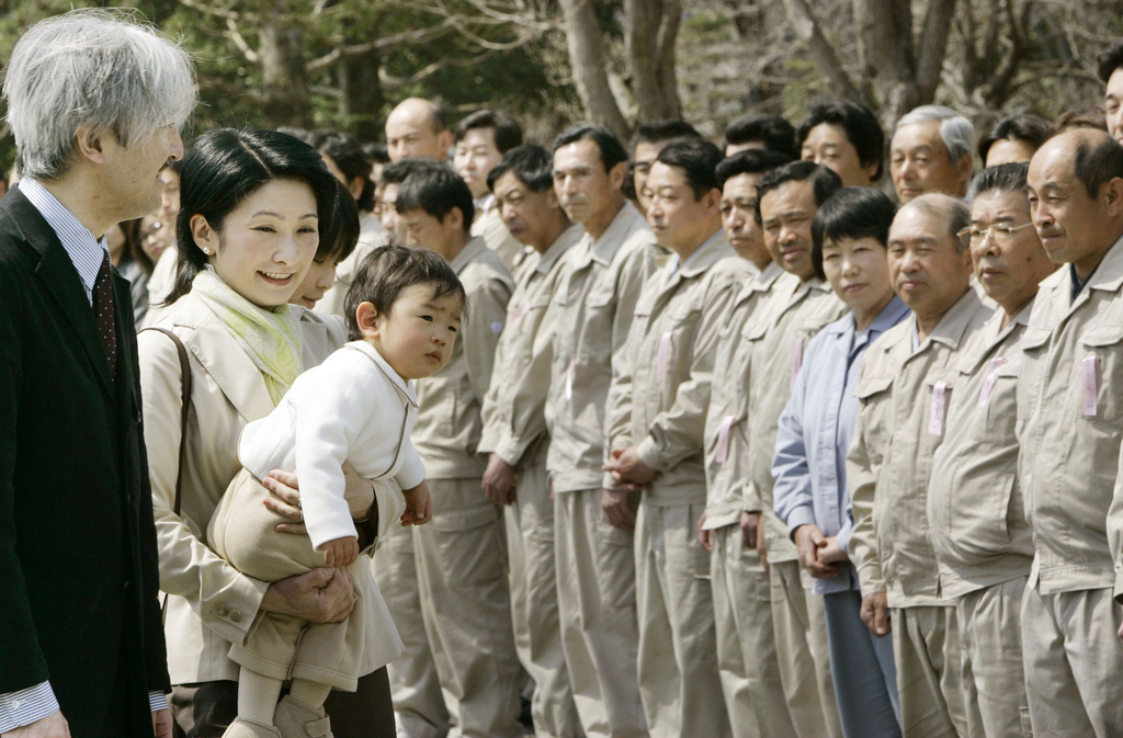FILE - Japan's Prince Akishino, left, and his wife Princess Kiko, carrying their son Prince Hisahito, are welcomed by the staff of an imperial ranch in Takanezawa, north of Tokyo, March 28, 2008. (AP Photo/Koji Sasahara, File)
